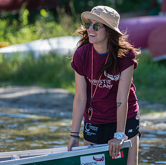Camp counciler smiling while leaning on a Canoe